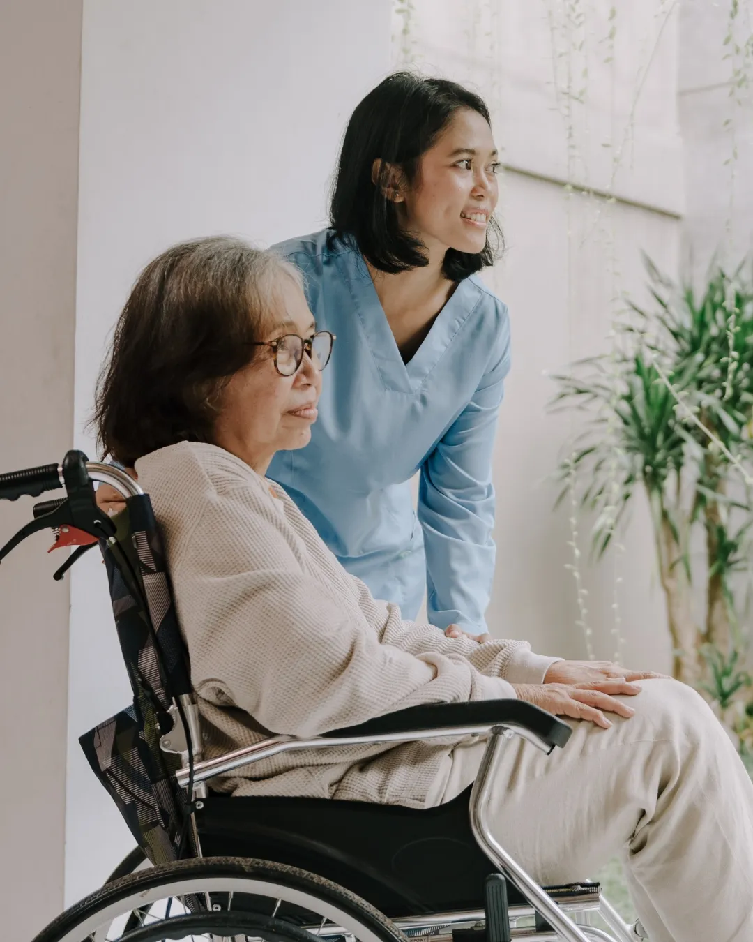 A carer wheeling an elderly patient through a warmly lit corridor